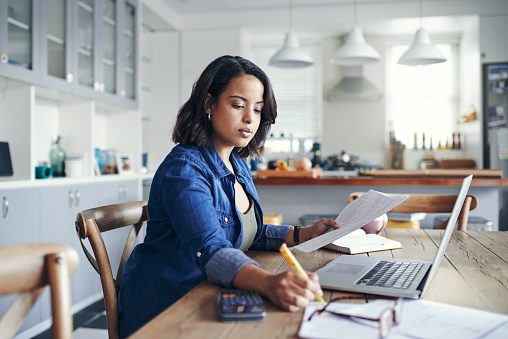 A woman sitting at the table writing on paper.