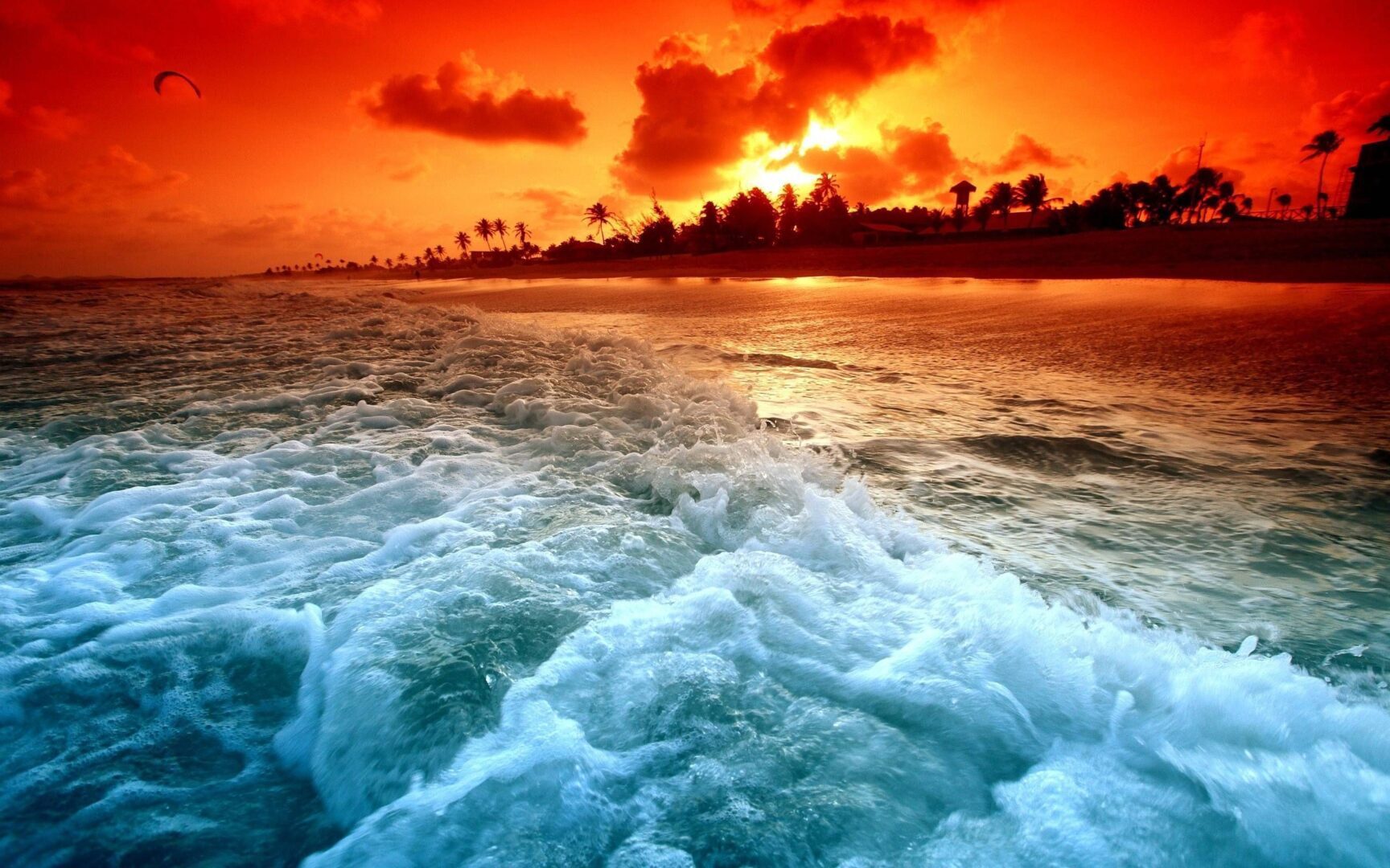 A sunset over the ocean with waves crashing in.